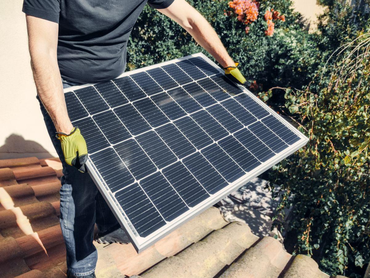 Monteur installiert ein Solarmodul auf einem Hausdach